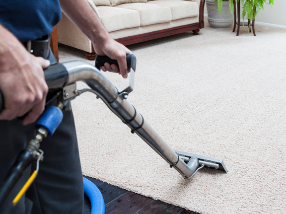 This is a photo of a man with a steam cleaner cleaning a cream carpet works carried out by Clapham Carpet Cleaning Solutions